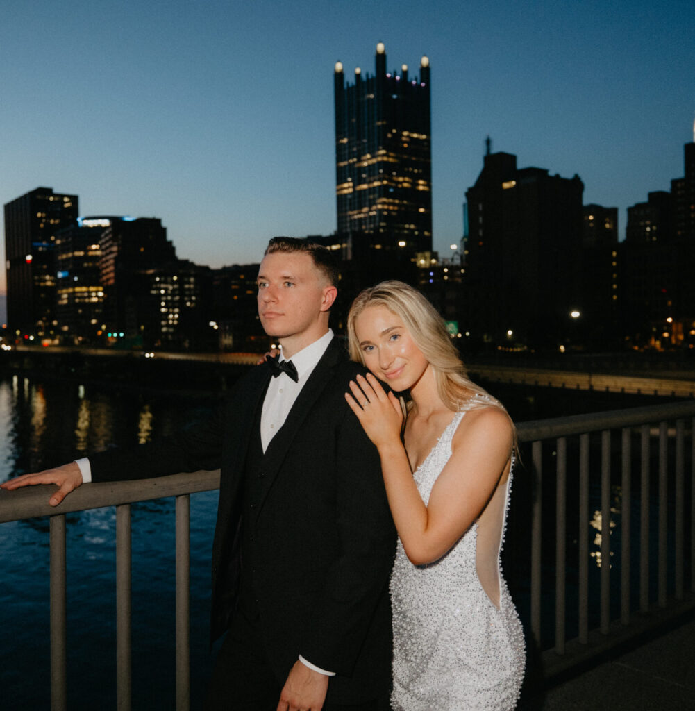 Picture of a man and woman posing on a bridge in Pittsburgh in black tie attire.